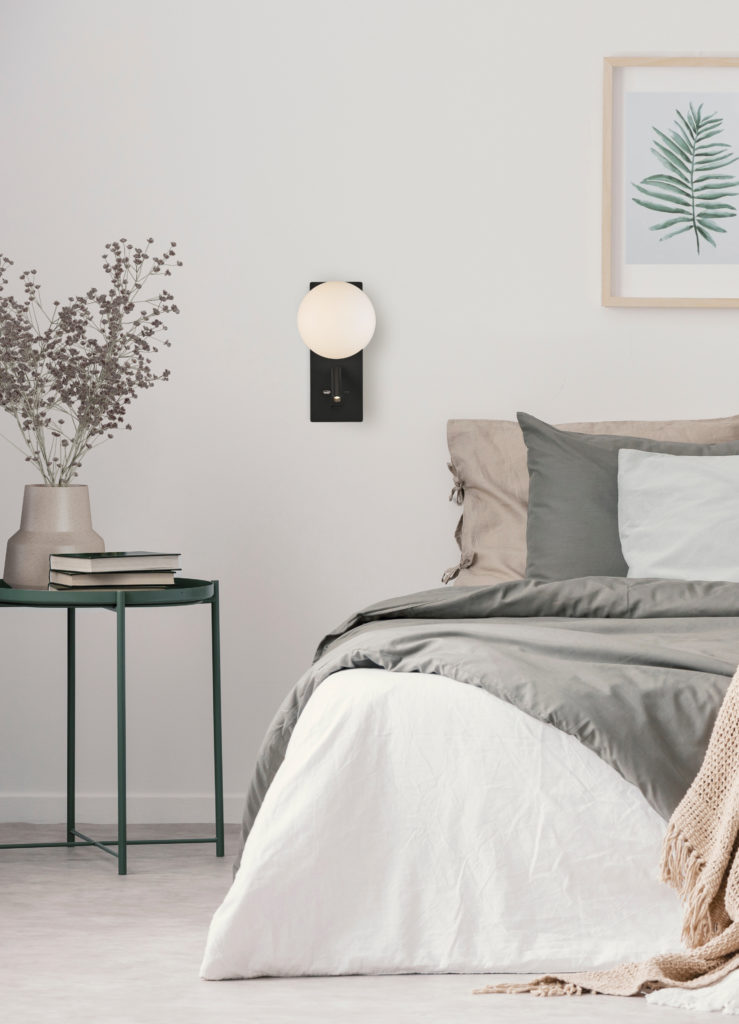 Flowers on table next to bed with pillows in white bedroom inter