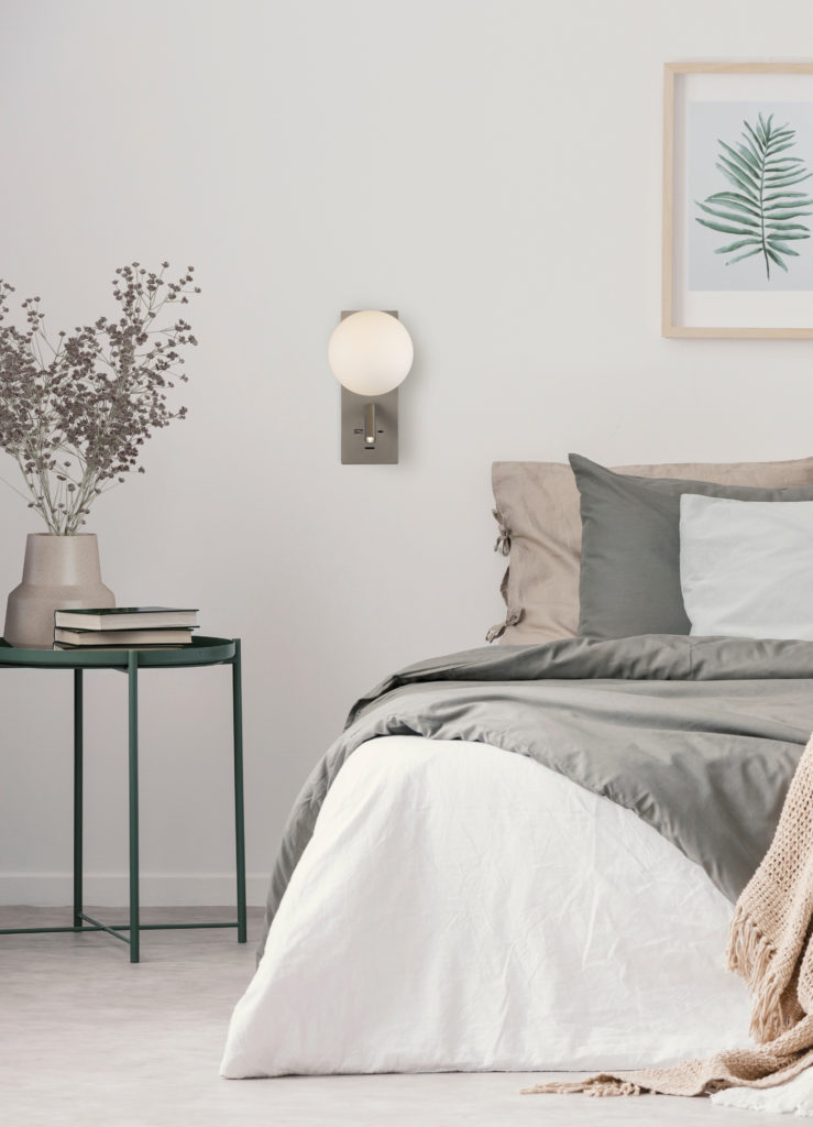 Flowers on table next to bed with pillows in white bedroom inter