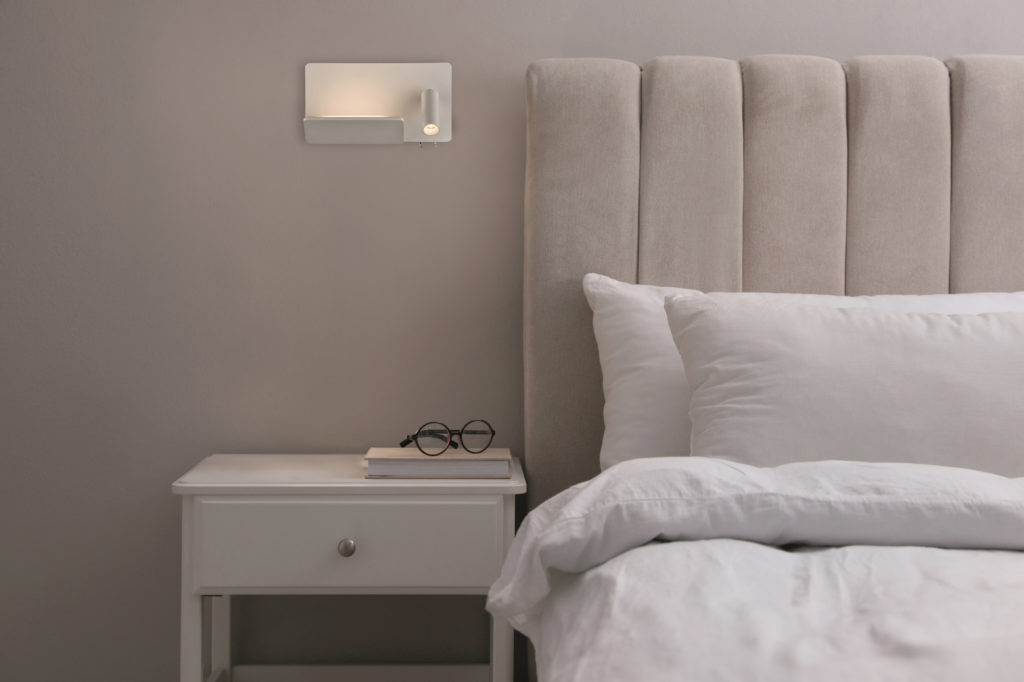 Stylish lamp, book and glasses on bedside table indoors. Bedroom