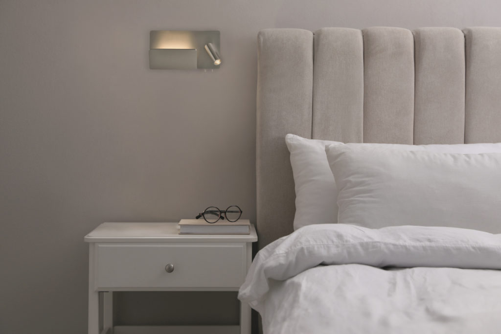 Stylish lamp, book and glasses on bedside table indoors. Bedroom