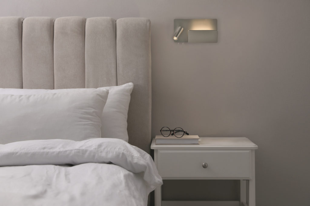 Stylish lamp, book and glasses on bedside table indoors. Bedroom