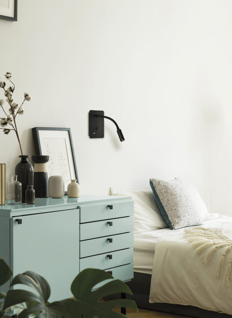 A white and beige color bedroom interior with a bed, a drawer ca