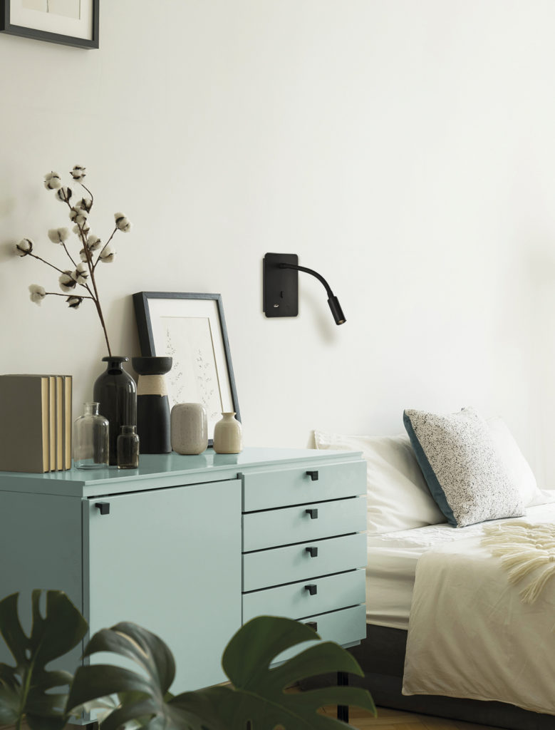 A white and beige color bedroom interior with a bed, a drawer ca